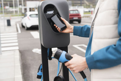 Man scanning and paying through smart phone at charging station