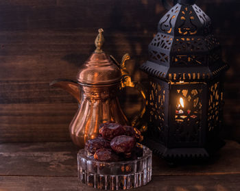 Close-up of antique teapot and lantern with raisins on table