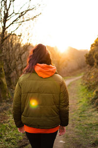 Rear view of beautiful woman standing against sky during sunset