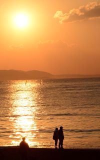 Silhouette of people in sea at sunset