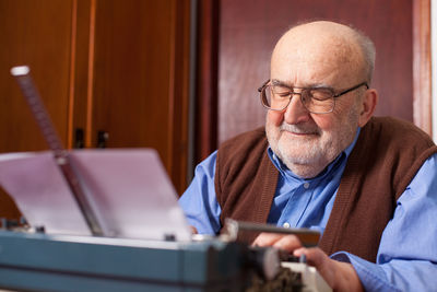 Senior man with typewriter against wall