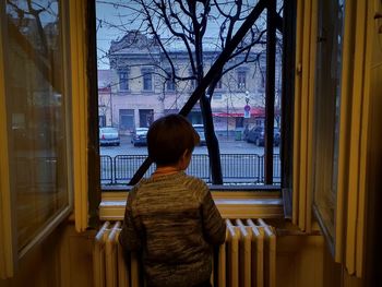 Rear view of man standing by window