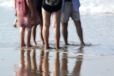 Low section of women standing on beach