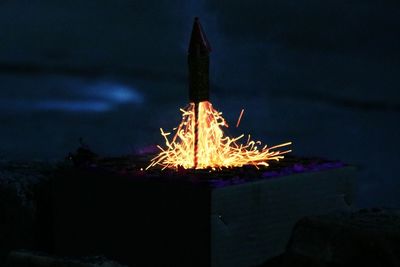 Close-up of illuminated fire against sky at night