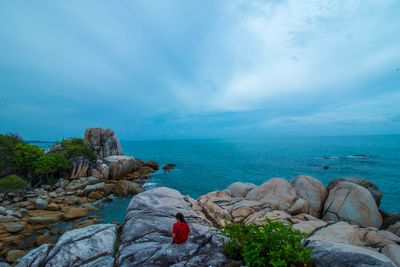 Rear view of rocks on beach against sky