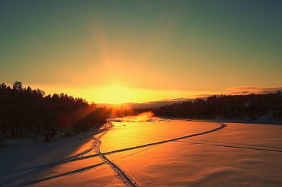 Snow covered trees against sky during sunset