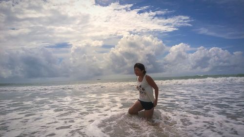 Woman sitting at beach against sky