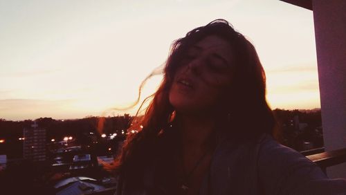 Close-up of man in city against sky at sunset