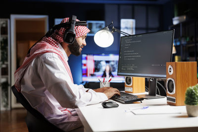 Midsection of man using laptop at desk in office