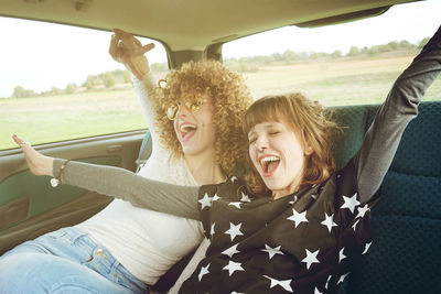 Cheerful female friends sitting in car