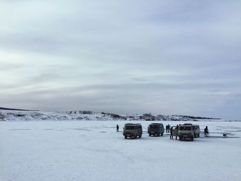 People and cars on snow field during winter