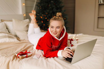 Smiling young woman using laptop on bed