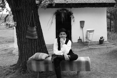 Portrait of smiling man sitting on seat against trees