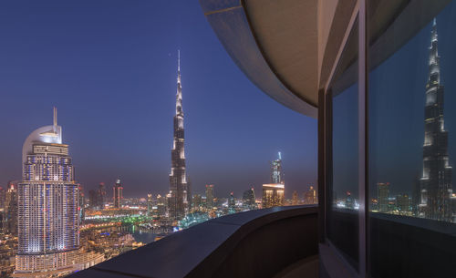 Illuminated city against sky seen from balcony at night