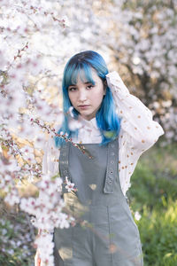 Portrait of beautiful woman standing by flowering plants