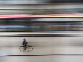 Blurred motion of man cycling on bicycle in city