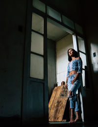 Full length of senior woman standing against door