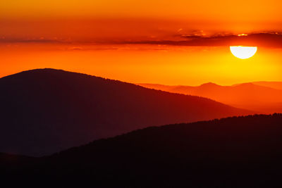 Scenic view of silhouette mountains against romantic sky at sunset