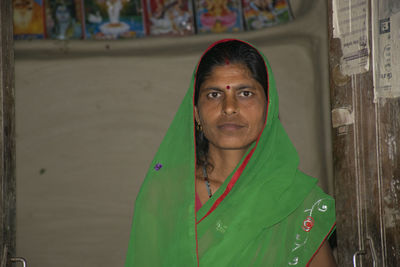 Portrait of indian village woman wearing saristanding against mud wall