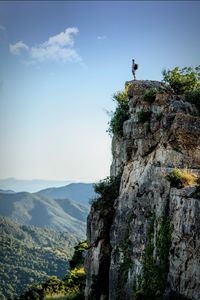 Scenic view of mountains against sky with man standing on rock