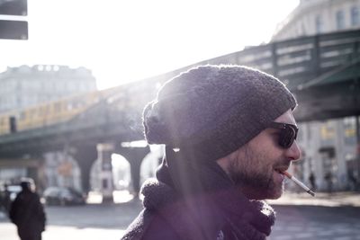 Side view of smiling young man smoking cigarette on street