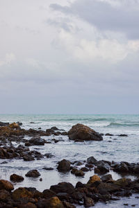 Scenic view of rocks on beach against sky