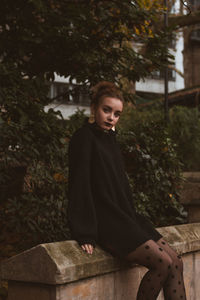 Portrait of young woman standing against trees