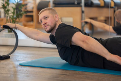 Male fitness pilates trainer shows exercises on special simulators. rubber rings for stretching