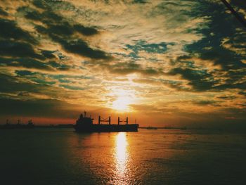 Silhouette boat in sea against sky during sunset