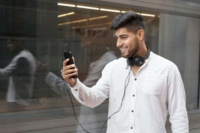 Young man using mobile phone while standing on mirror