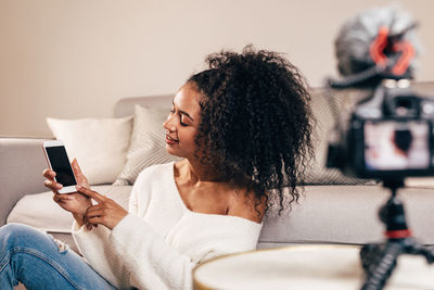 Woman using phone while sitting on sofa at home