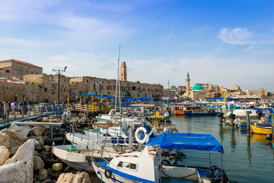 Boats moored in harbor against buildings in city