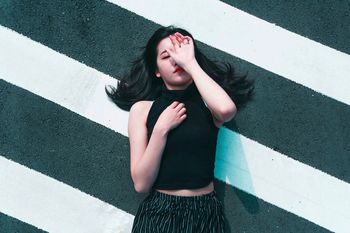 HIGH ANGLE VIEW OF YOUNG WOMAN WITH HAND IN MIRROR