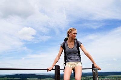 Young woman sitting on railing at observation point