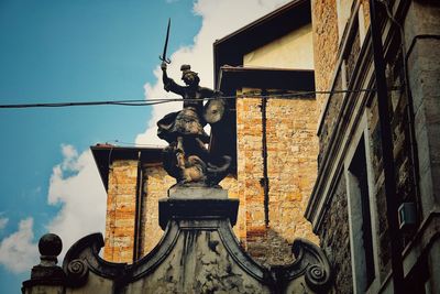 Low angle view of old statue against building