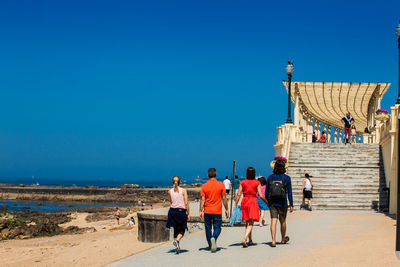 People on beach against clear blue sky