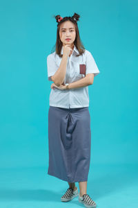 Portrait of woman standing against blue background