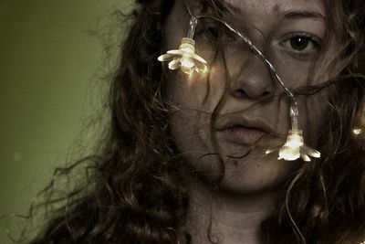 Close-up portrait of young woman with lights on face