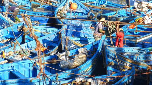 High angle view of people working on blue fishing boats at port