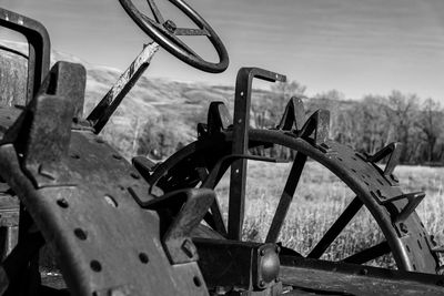Close-up of rusty wheel on field against sky