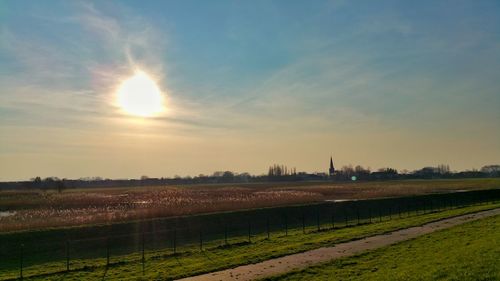 Scenic view of grassy field against sky at sunset