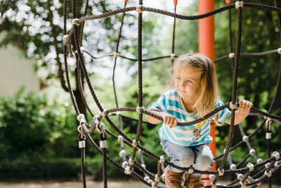 Full length of girl playing inside climbing rope at park