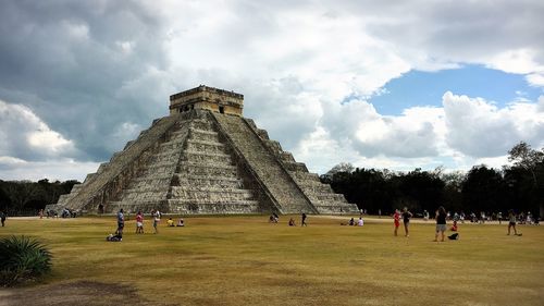 Group of people in front of historical building against cloudy sky