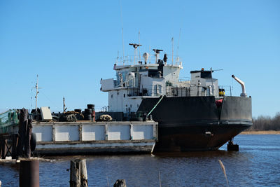 Ship moored on sea against clear blue sky