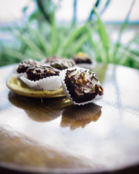 Chocolate brownie cubes with chocolate drizzle in paper cups on a wooden background.