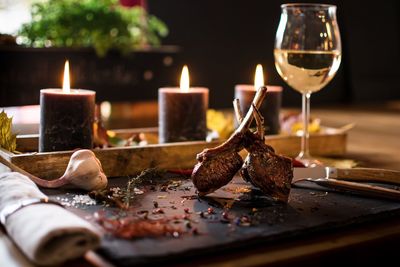 Close-up of meat in tray with wine by candles on table