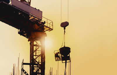 Low angle view of silhouette crane against sky during sunset