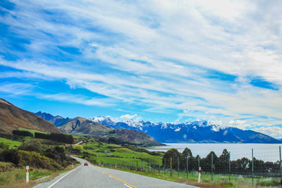 Road by mountains against sky