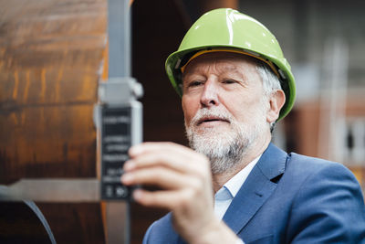 Male manager measuring metal with caliper in warehouse