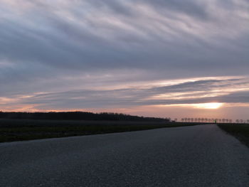 Road by landscape against sky during sunset